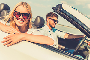 Feeling relaxed and free. Happy young woman leaning at the vehic Führerschein